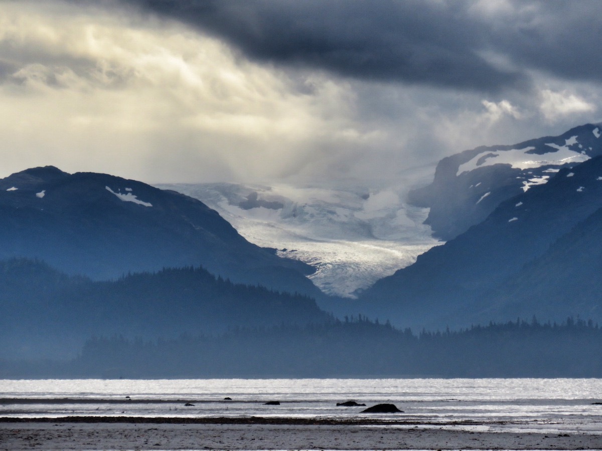 Image of a retreating glacier nestled across water. Taken on a beach on a stormy day.